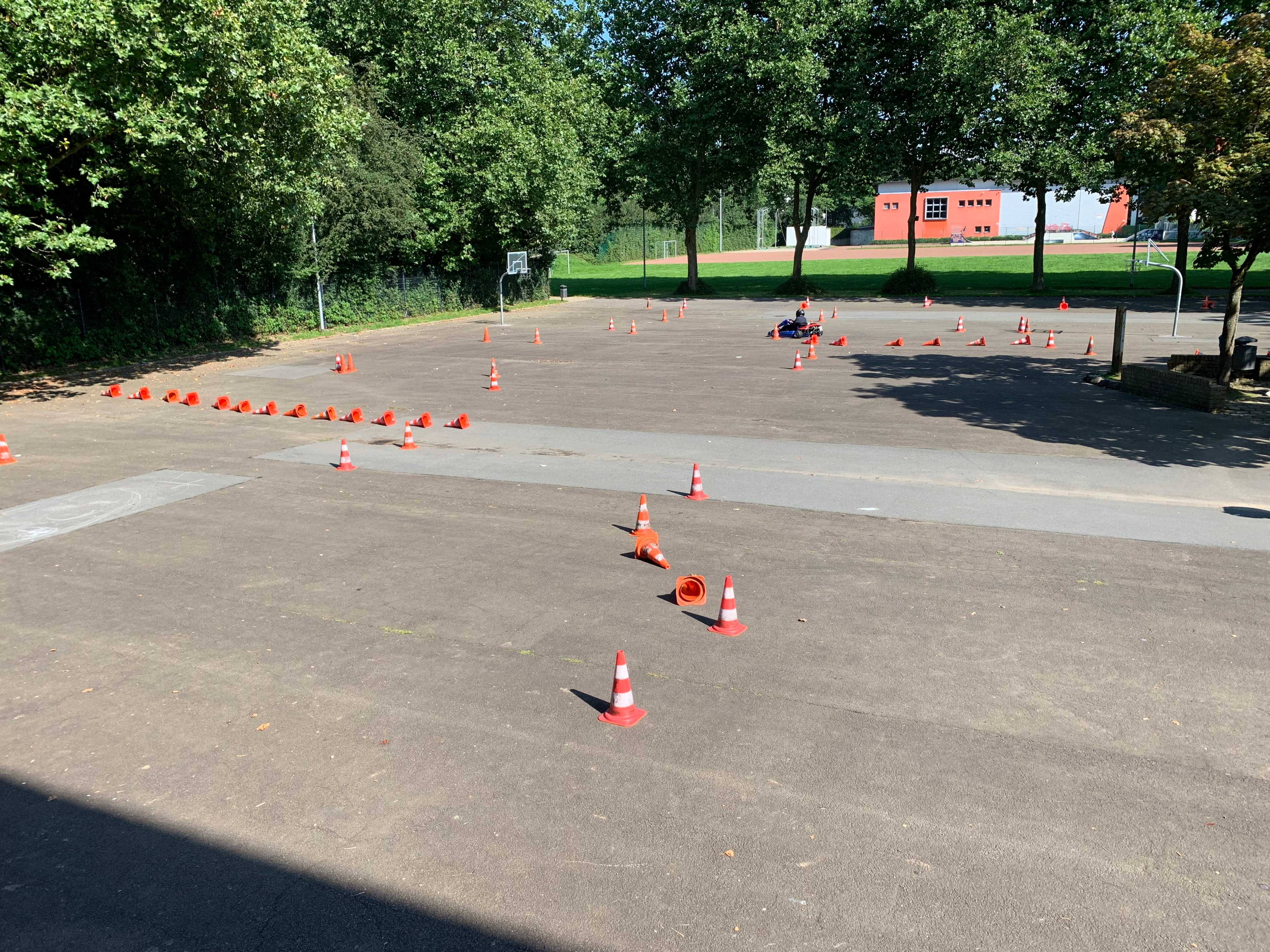 Ein Kart fährt durch einen aufgebauten Parcour auf dem Schulhof in Böddinghausen.