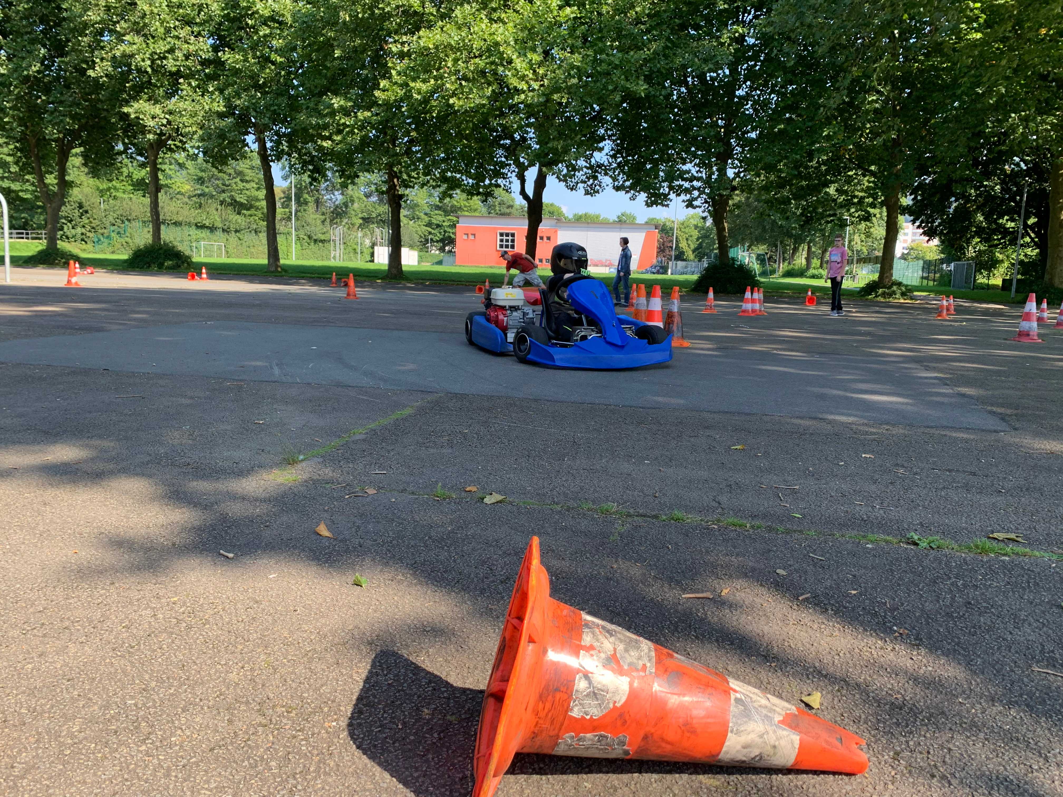 Ein Kart fährt durch einen aufgebauten Parcour auf dem Schulhof in Böddinghausen.